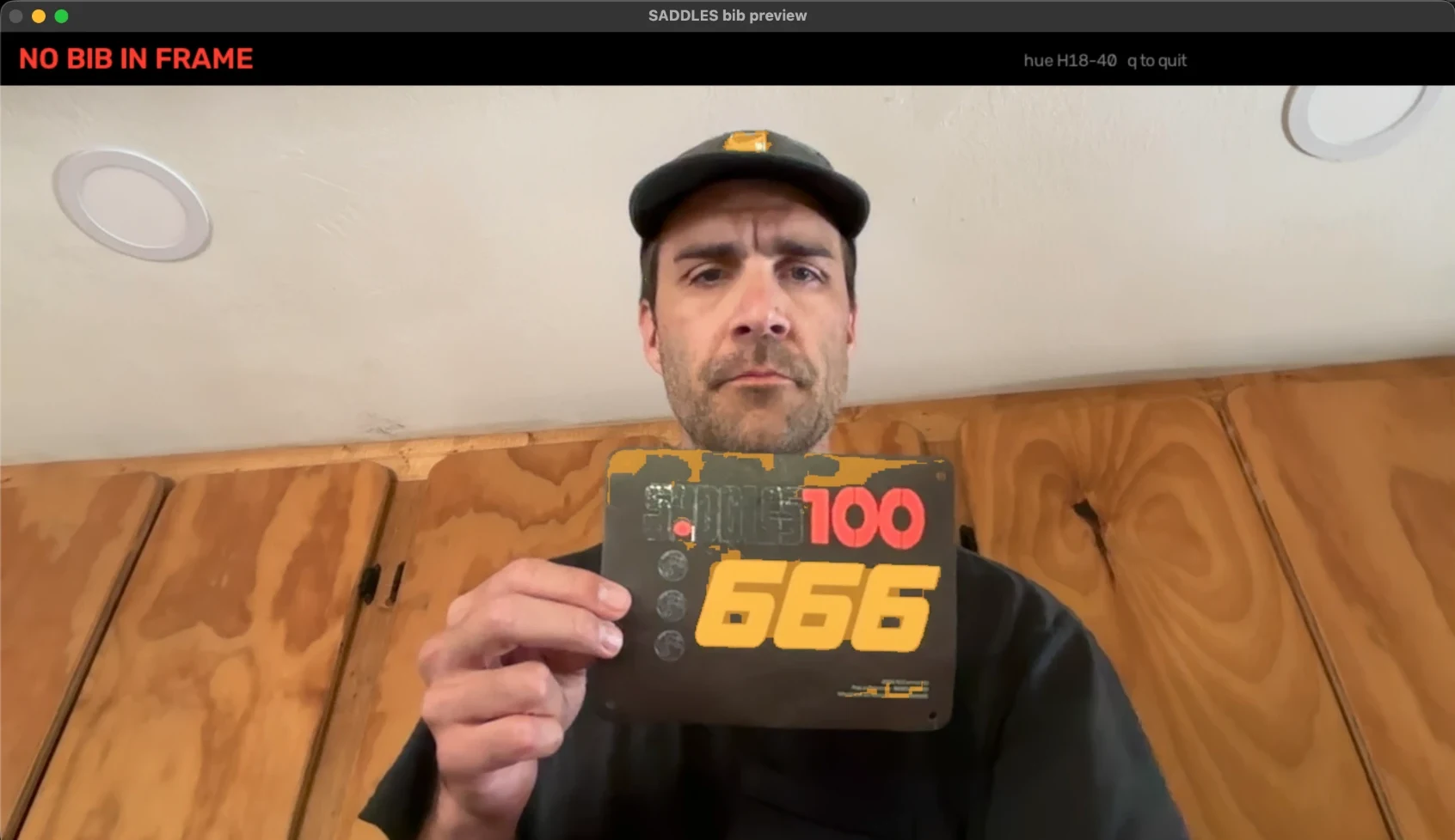 The bib preview dev tool: a webcam frame with NO BIB IN FRAME in red, James holding a Saddles 666 bib with the chroma mask keyed to the bib stock, hue range 18 to 40 in the corner